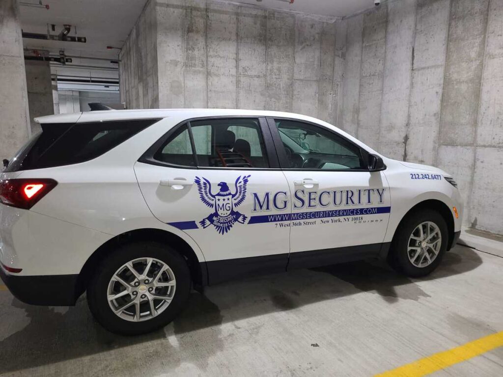 White SUV with blue vinyl vehicle wrap graphics and security company branding.
