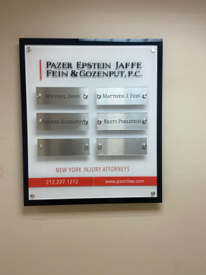 Framed office directory sign with metal name plates mounted on wall.