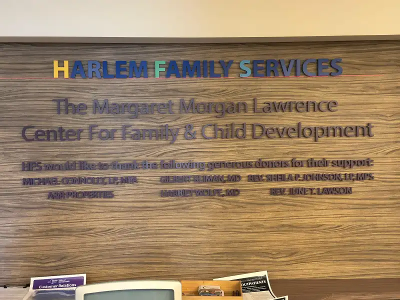 Colorful acrylic dimensional lettering for Harlem Family Services on wood-paneled lobby wall, Manhattan, NY