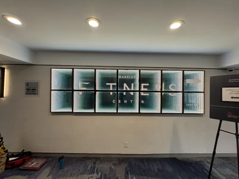 Illuminated infinity mirror lightbox sign for Marriott Fitness Center with directional arrow in hotel hallway, Manhattan, NY