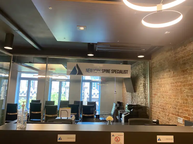 Hanging acrylic dimensional sign for New York Spine Specialist above glass office partition, Brooklyn, NY
