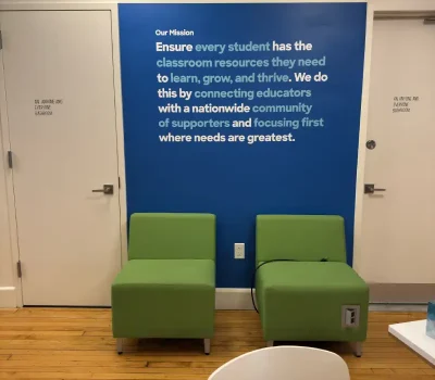 Cut vinyl wall mural with DonorsChoose mission statement in blue and white lettering, office lounge in Manhattan, NY